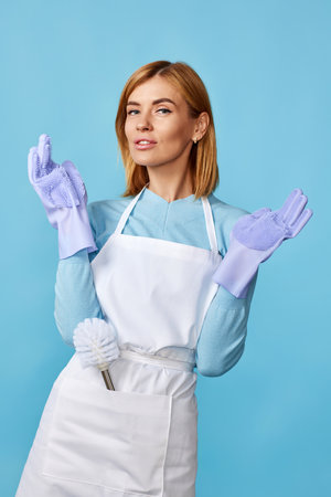 woman in rubber gloves and cleaner apron holding toilet brushの写真素材