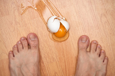 broken egg and feet on the floor in kitchenの写真素材