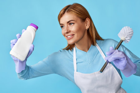 woman in rubber gloves holding toilet brush and bottle of detergentの写真素材