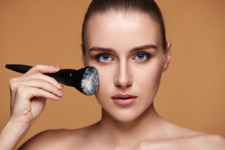 woman applying powder with professional make-up brushの写真素材