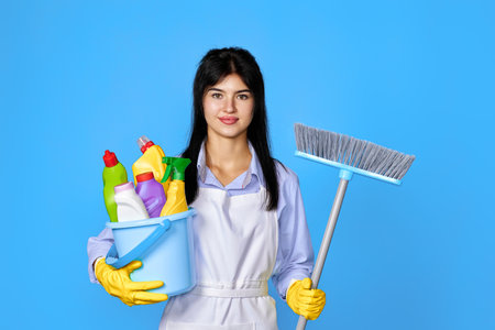 woman in gloves holding bucket of detergents and broomの写真素材