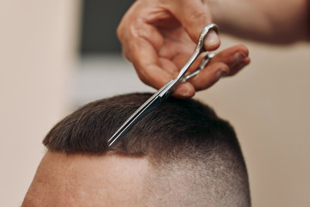 hairdresser does hairstyle with scissors in barber shopの写真素材