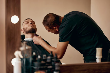 Barber shaving caucasian man in barber shopの写真素材