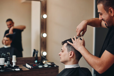 hairdresser does haircut for man in barber shopの写真素材