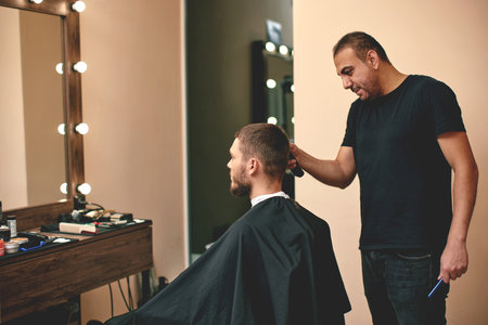 Barber shaving caucasian man in barber shopの写真素材