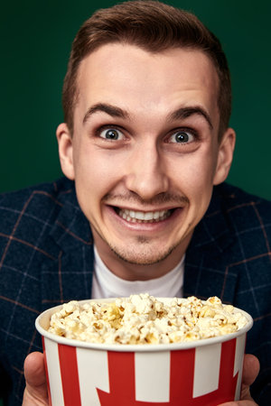 Young caucasian man in 3d glasses eating popcornの写真素材