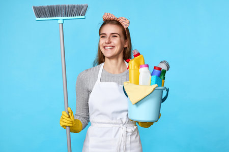 woman in gloves holding bucket of detergents and broomの写真素材