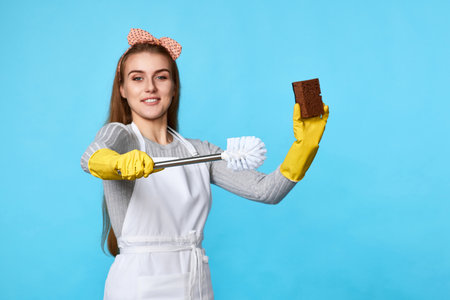 woman in rubber gloves and cleaner apron cleaning with spongeの写真素材