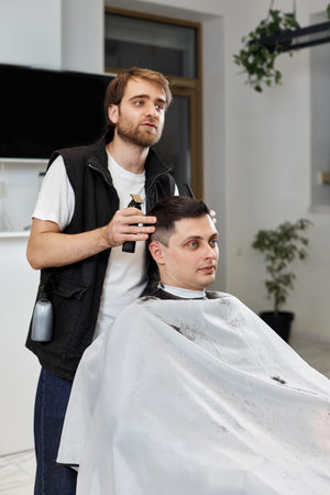 Barber shaving caucasian man in barber shop.の写真素材