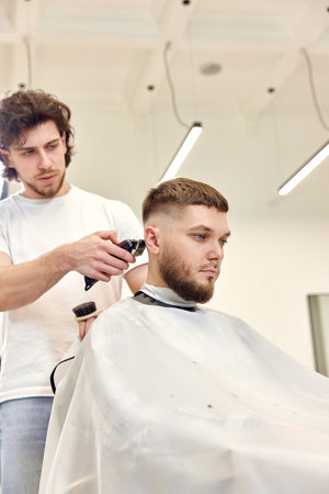 Barber trim hair with clipper on handsome bearded manの写真素材