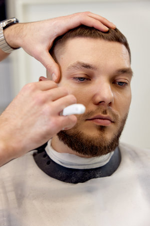 Barber shaving bearded man with retro knifeの写真素材