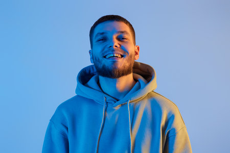 handsome bearded man in sweatshirt on blue background.