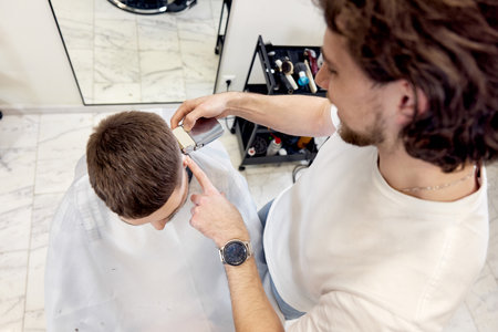 Barber trim hair with clipper on handsome bearded manの写真素材