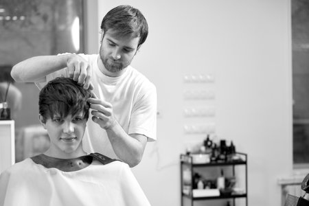 caucasian man getting haircut by professional male hairstylistの写真素材