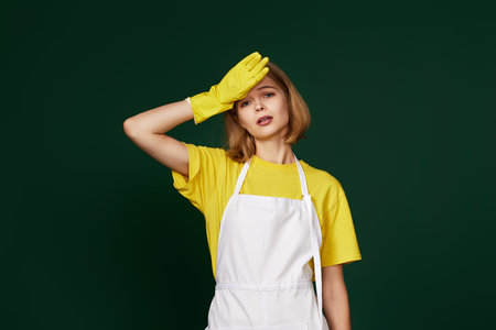 tired woman in yellow gloves and cleaner apronの写真素材