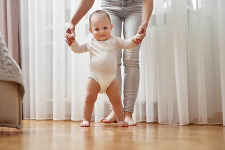 happy little baby girl learning to walk with mother help