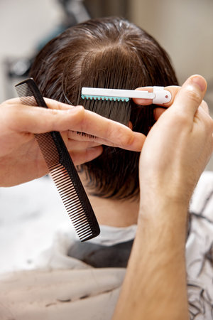 young caucasian man getting haircut by professional male hairstylistの写真素材