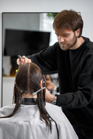Professional male hairdresser cutting female hair in salonの写真素材