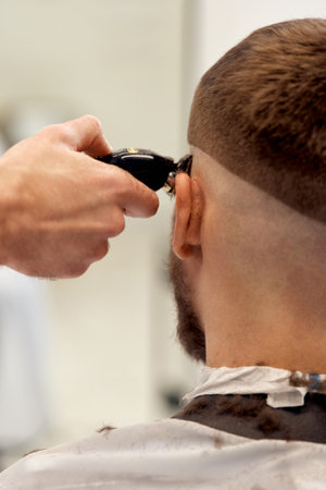 Barber trim hair with clipper on handsome bearded manの写真素材