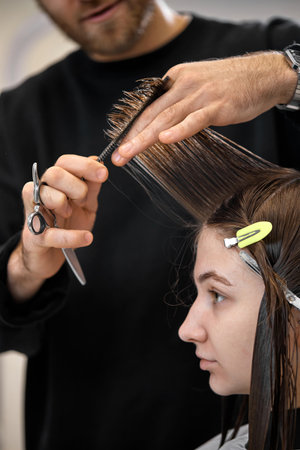 Professional male hairdresser cutting female hair in salonの写真素材