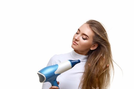Portrait of attractive cheerful girl drying long hairの写真素材