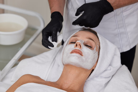 beautician cleanses skin of woman with cotton sponge. .の写真素材