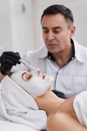 beautician applies the mask to face of woman in the spa salon. skin careの写真素材