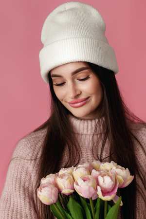 pretty woman in white hat, sweater holding bouquet of tulip