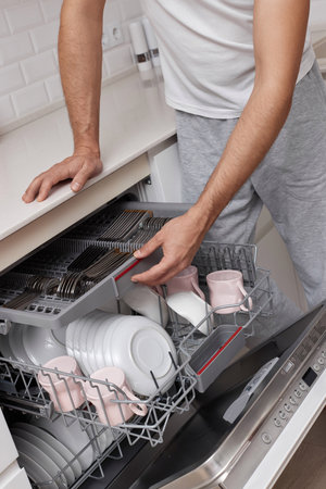 close-up, man unloading dishwasher machine in the kitchenの写真素材
