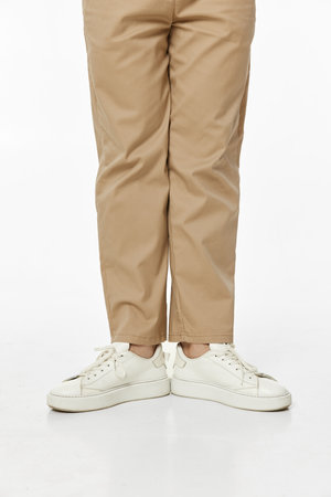 man wearing white sneakers and casual beige pants on studio background, front viewの写真素材