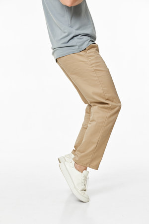 man wearing white sneakers and casual beige pants on studio background. side view