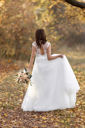 beautiful happy bride holding wedding autumn bouquet in natureの写真素材