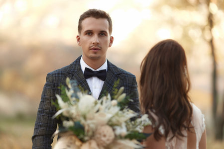 portrait of bride in white wedding dress and groom standing outdoor on natural backgroundの写真素材