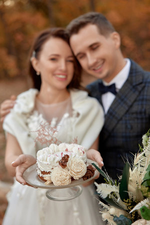 bride and groom on the nature in autumn . wedding couple with cake outdoorの写真素材