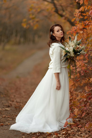 beautiful happy bride holding wedding autumn bouquet in natureの写真素材