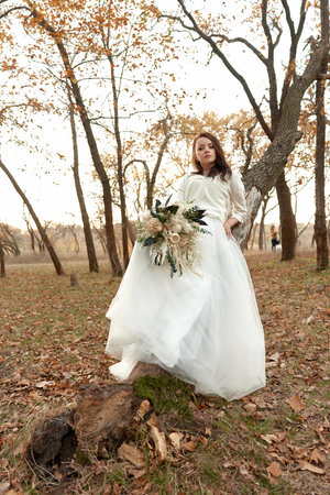 beautiful happy bride holding wedding autumn bouquet in natureの写真素材