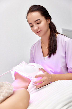 woman getting cosmetic procedure with LED anti-aging facial maskの写真素材