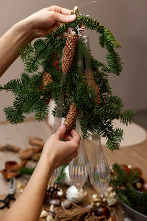 Woman making Christmas arrangement with fir branches, pine cones and bow. craft handmade decor.の写真素材