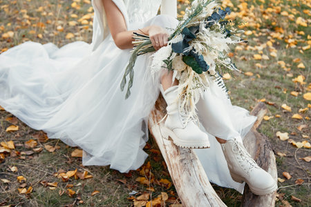 bride wearing white boots holding beautiful autumn bouquet. copy spaceの写真素材