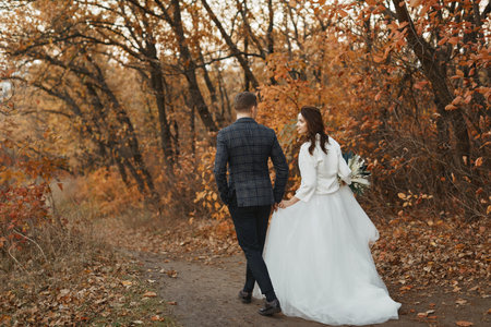 bride and groom walking outside in autumnの写真素材