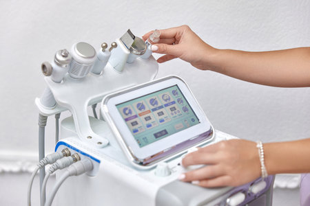 female beautician using cosmetology equipment in modern aesthetic clinic.の写真素材