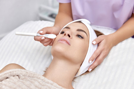 female hand touching the patients face with a brush. beautician applies the mask to female face. facial skin care.の写真素材