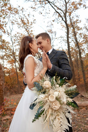 beautiful sensual bride in white wedding dress and groom standing outdoor on natural backgroundの写真素材
