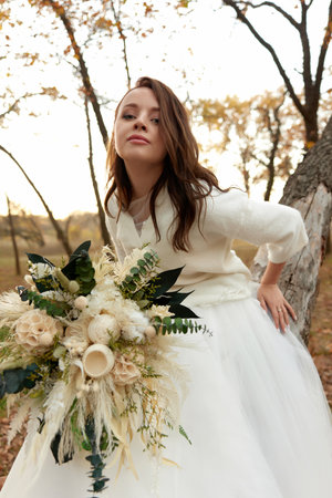 beautiful happy bride holding wedding autumn bouquet in natureの写真素材