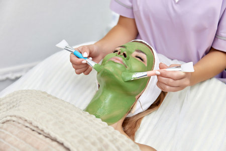 female beautician applies the mask to the face of beautiful woman in the spa salon. facial skin careの写真素材