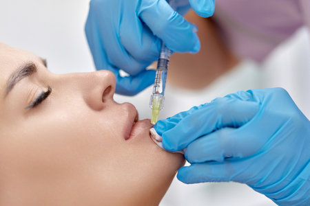 cosmetologist makes injections to enlarge the lips of beautiful woman. procedure lip augmentationの写真素材