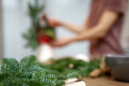 blur background of Woman making Christmas arrangement with fir branches. focus on fir branchの写真素材
