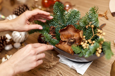 Female hands creating Christmas craft handmade decor with fir branches.の写真素材