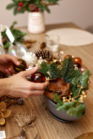Female hands creating Christmas craft handmade decor with fir branches and dried flowersの写真素材