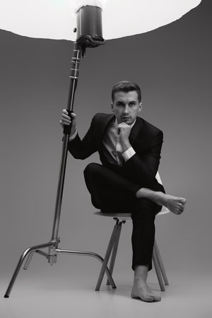 elegant model man in black suit barefoot in photostudio. black and whiteの写真素材